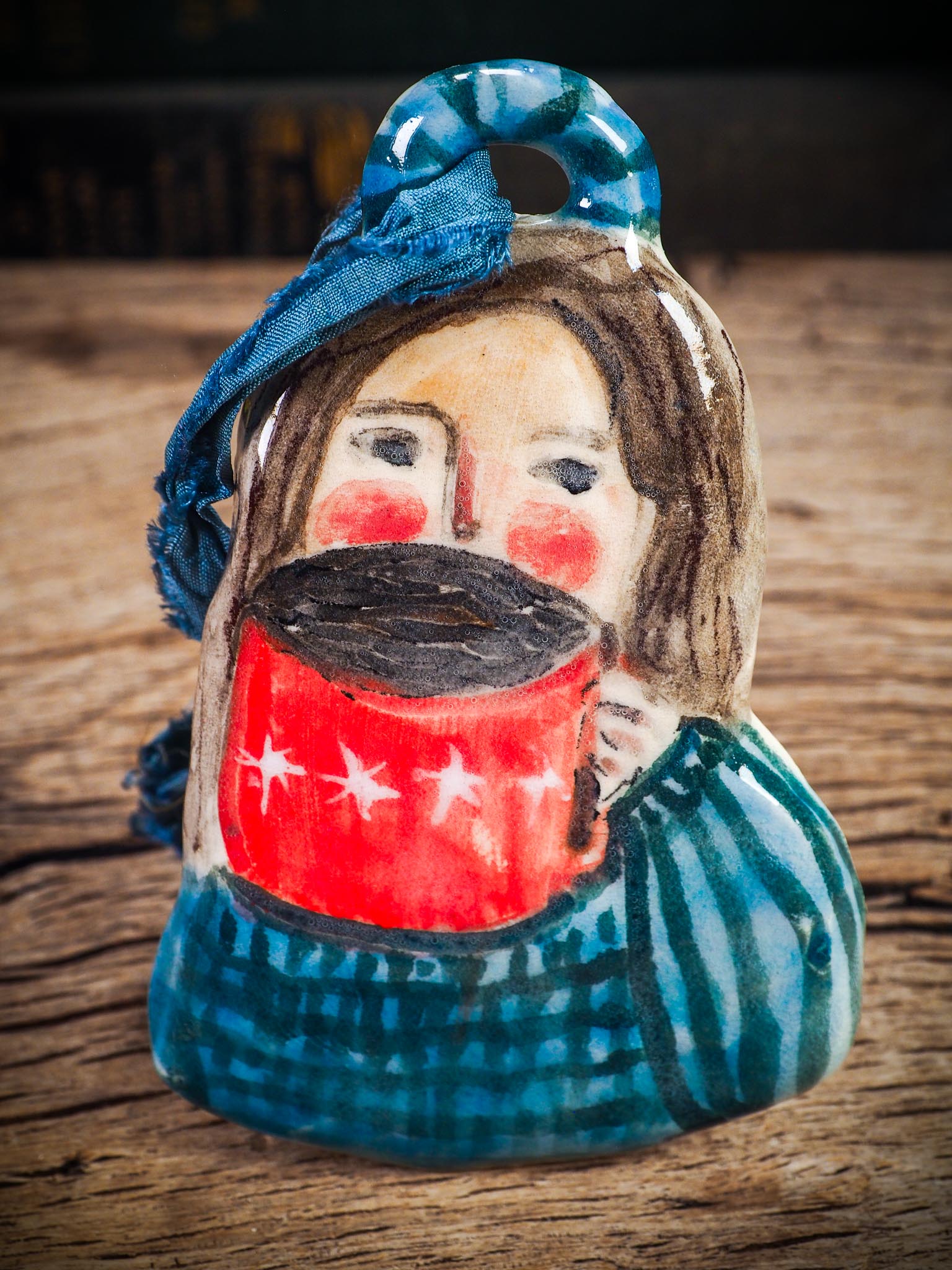 Handmade ceramic hot cocoa woman figure ornament with red mug and blue clothing, created by Idania Salcido aka Danita Art for Christmas decorating or gifting.