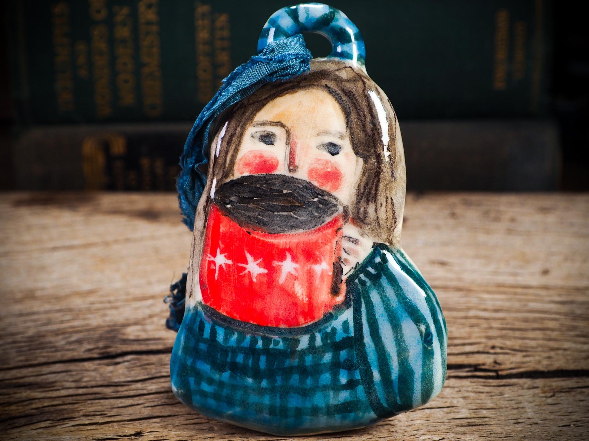 Handmade ceramic hot cocoa woman figure ornament with red mug and blue clothing, created by Idania Salcido aka Danita Art for Christmas decorating or gifting.