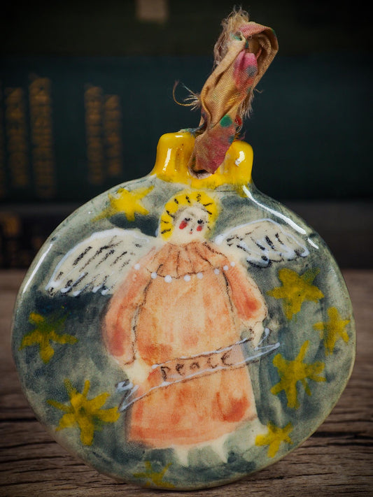 Handmade ceramic Peace Angel ornament with wings and golden halo, created by Idania Salcido aka Danita Art for Christmas decorating or gifting.