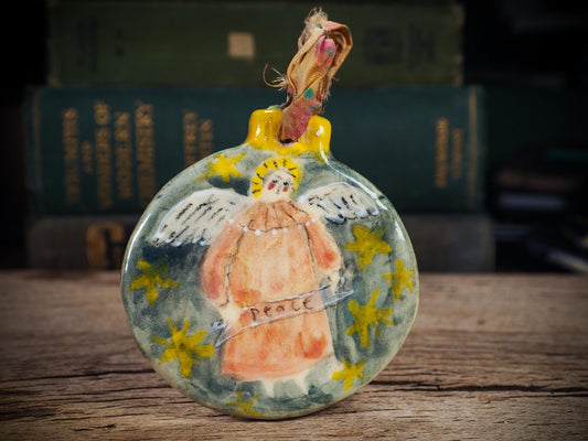 Handmade ceramic Peace Angel ornament with wings and golden halo, created by Idania Salcido aka Danita Art for Christmas decorating or gifting.