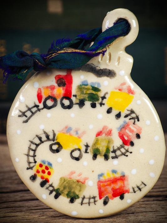 Handmade ceramic holiday train ornament with colorful cars and snowy details, created by Idania Salcido aka Danita Art for Christmas decoration or gifting.