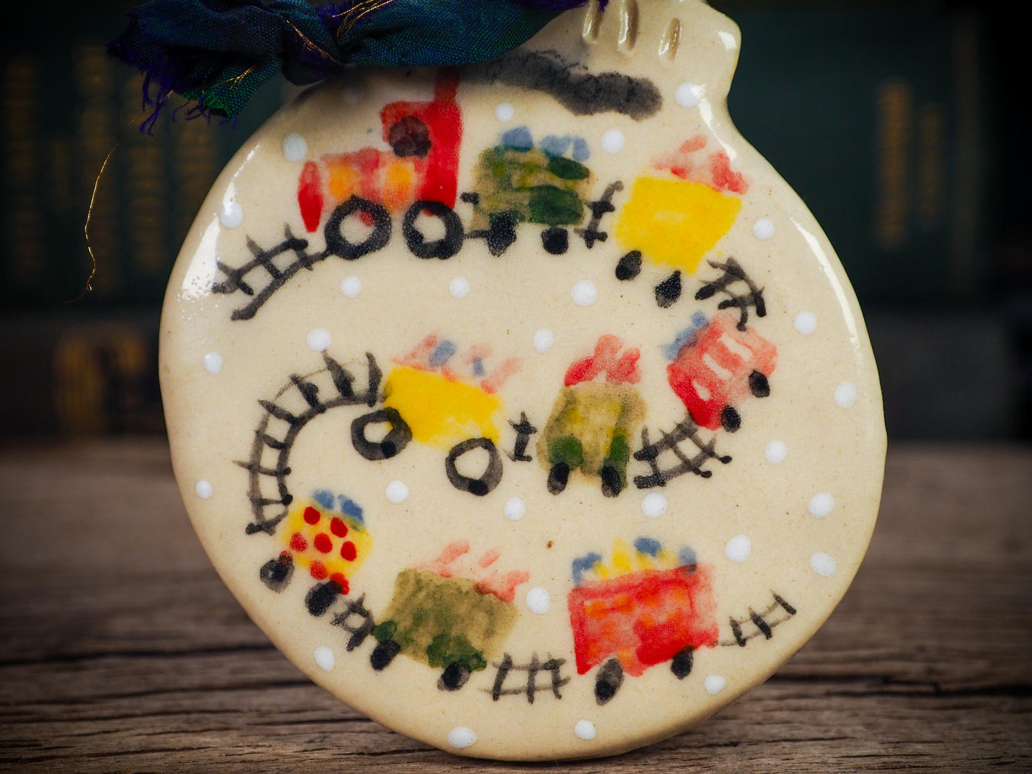 Handmade ceramic holiday train ornament with colorful cars and snowy details, created by Idania Salcido aka Danita Art for Christmas decoration or gifting.