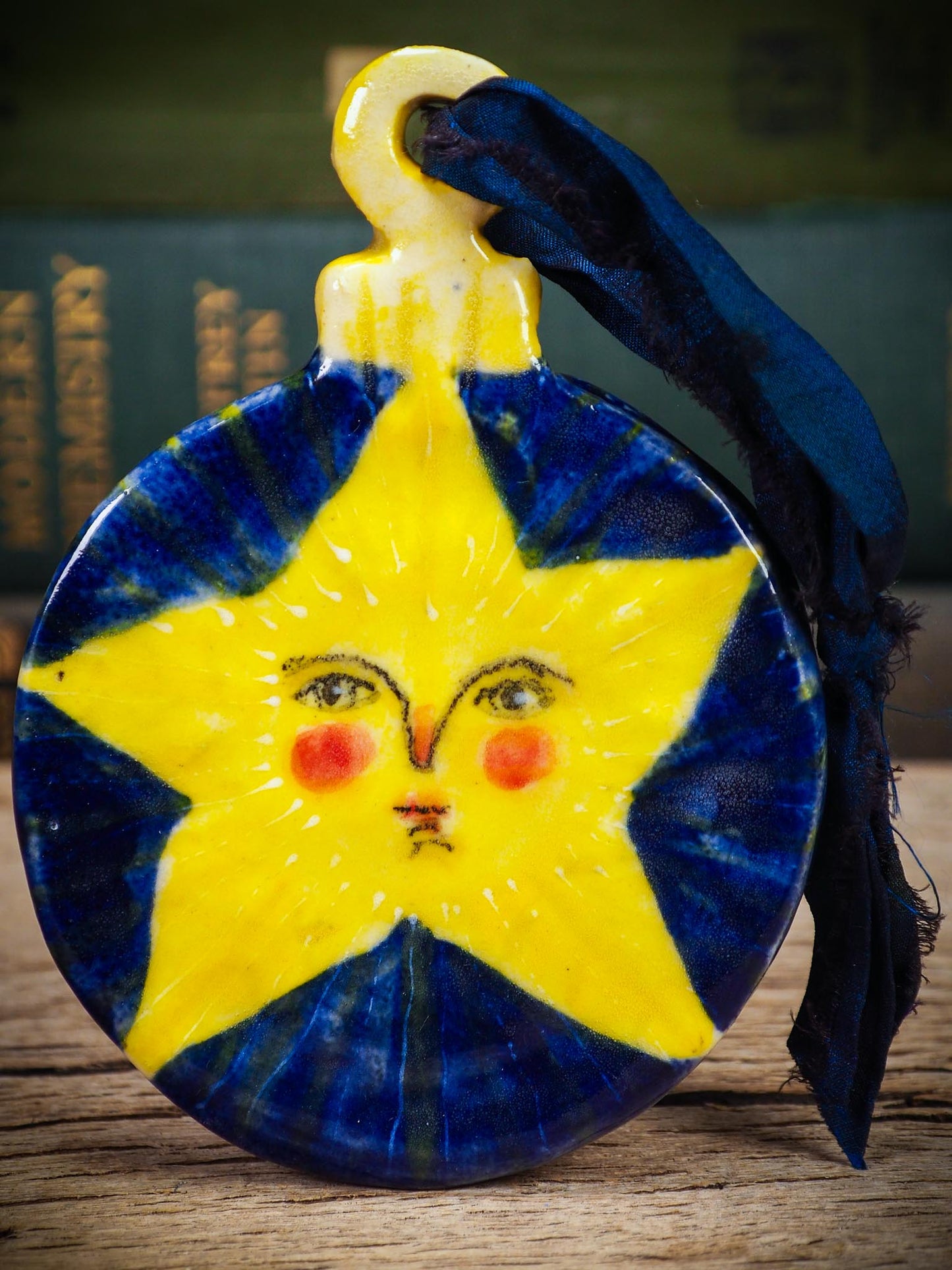 Handmade ceramic star ornament with painted face and deep blue background by Idania Salcido aka Danita Art.