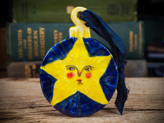 Handmade ceramic star ornament with painted face and deep blue background by Idania Salcido aka Danita Art.