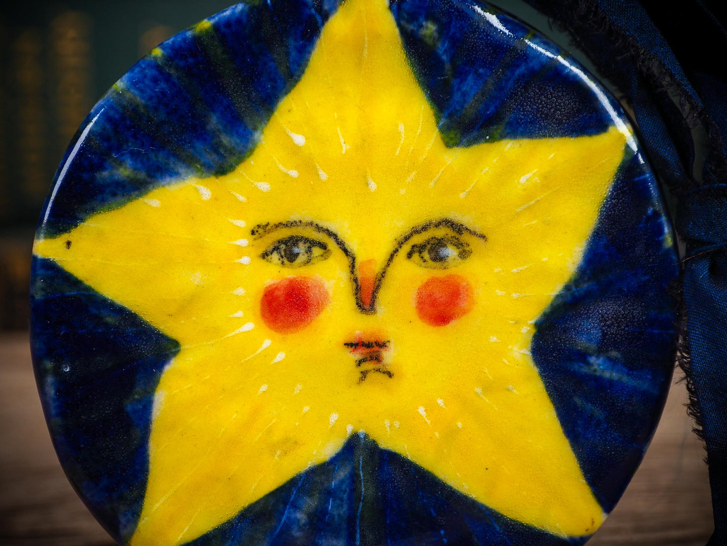 Handmade ceramic star ornament with painted face and deep blue background by Idania Salcido aka Danita Art.
