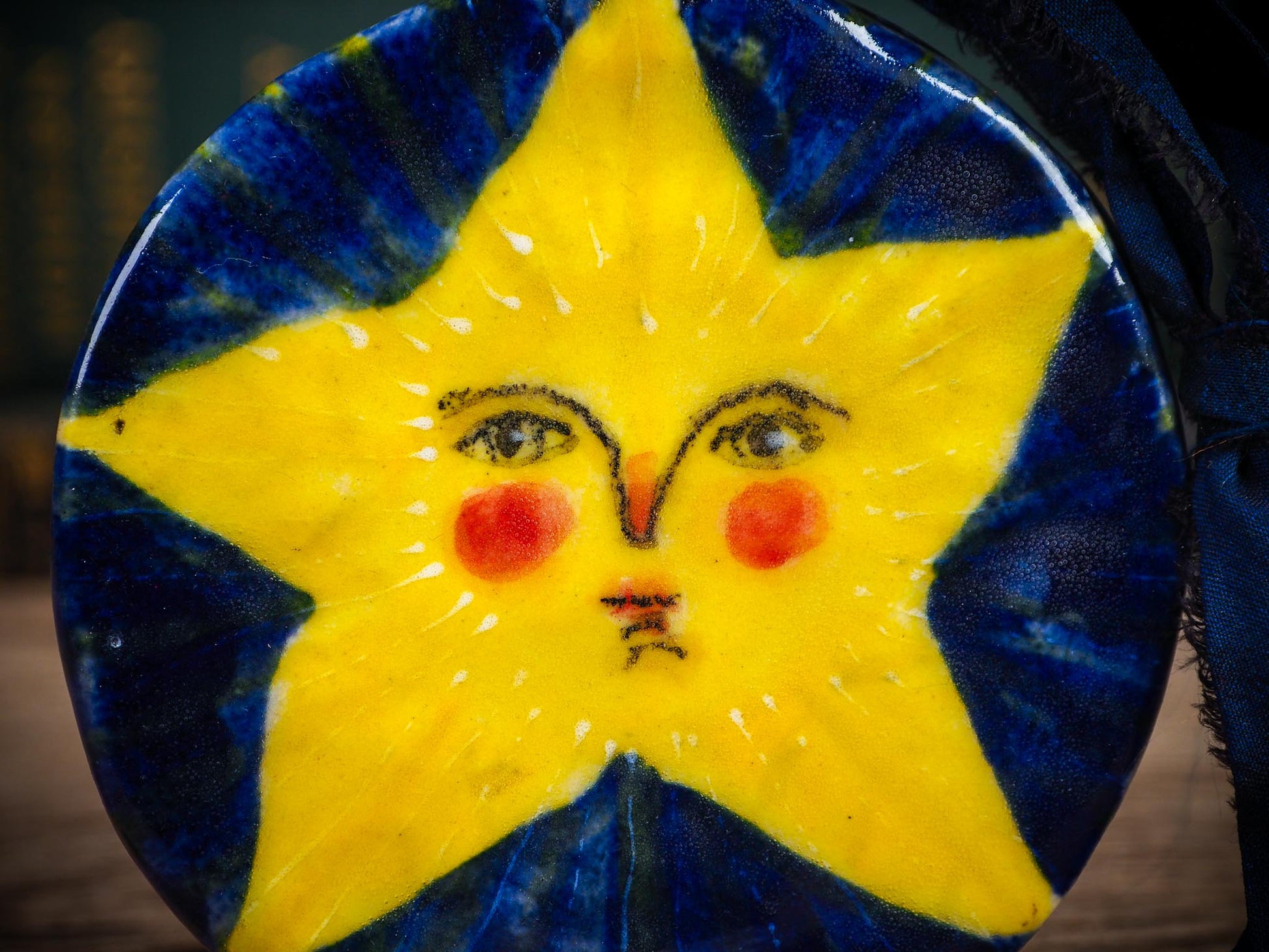 Handmade ceramic star ornament with painted face and deep blue background by Idania Salcido aka Danita Art.