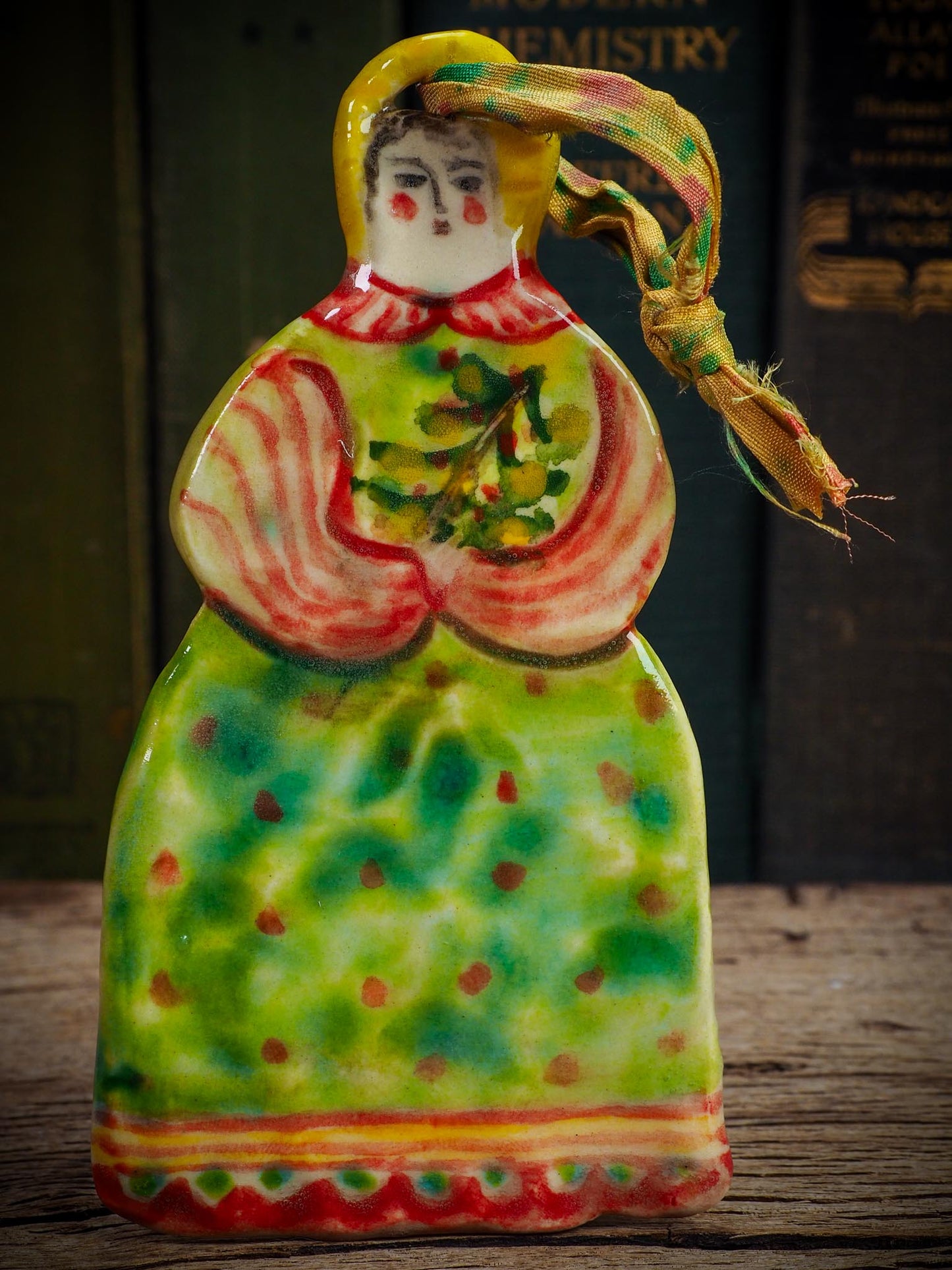 Handmade ceramic winter figure ornament with green dress and painted details, created by Idania Salcido aka Danita Art for Christmas decoration or gifting.