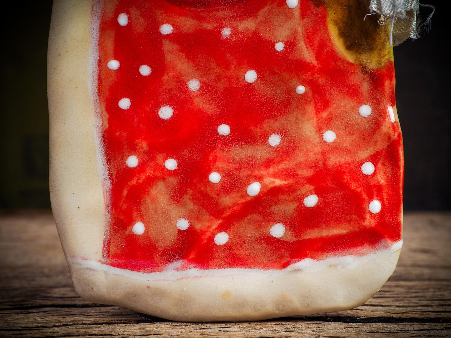 Handmade ceramic winter figure ornament with red dotted coat and ribbon, created by Idania Salcido AKA Danita Art for Christmas decorating or gifting.