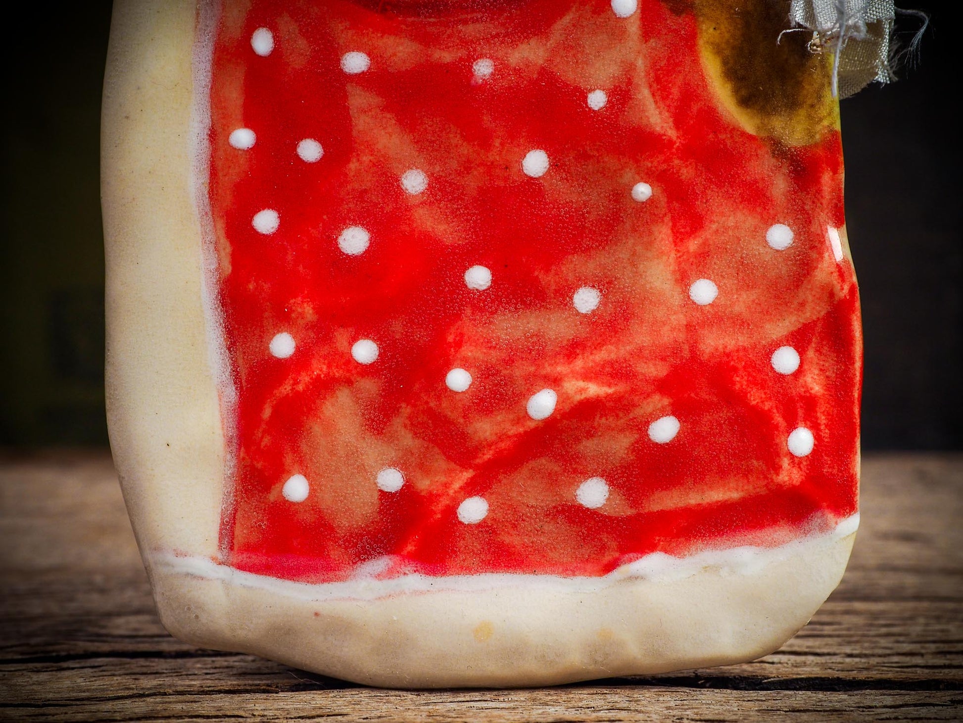 Handmade ceramic winter figure ornament with red dotted coat and ribbon, created by Idania Salcido AKA Danita Art for Christmas decorating or gifting.