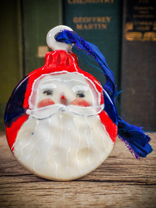 Handmade ceramic Santa ornament with blue ribbon by Idania Salcido aka Danita Art.