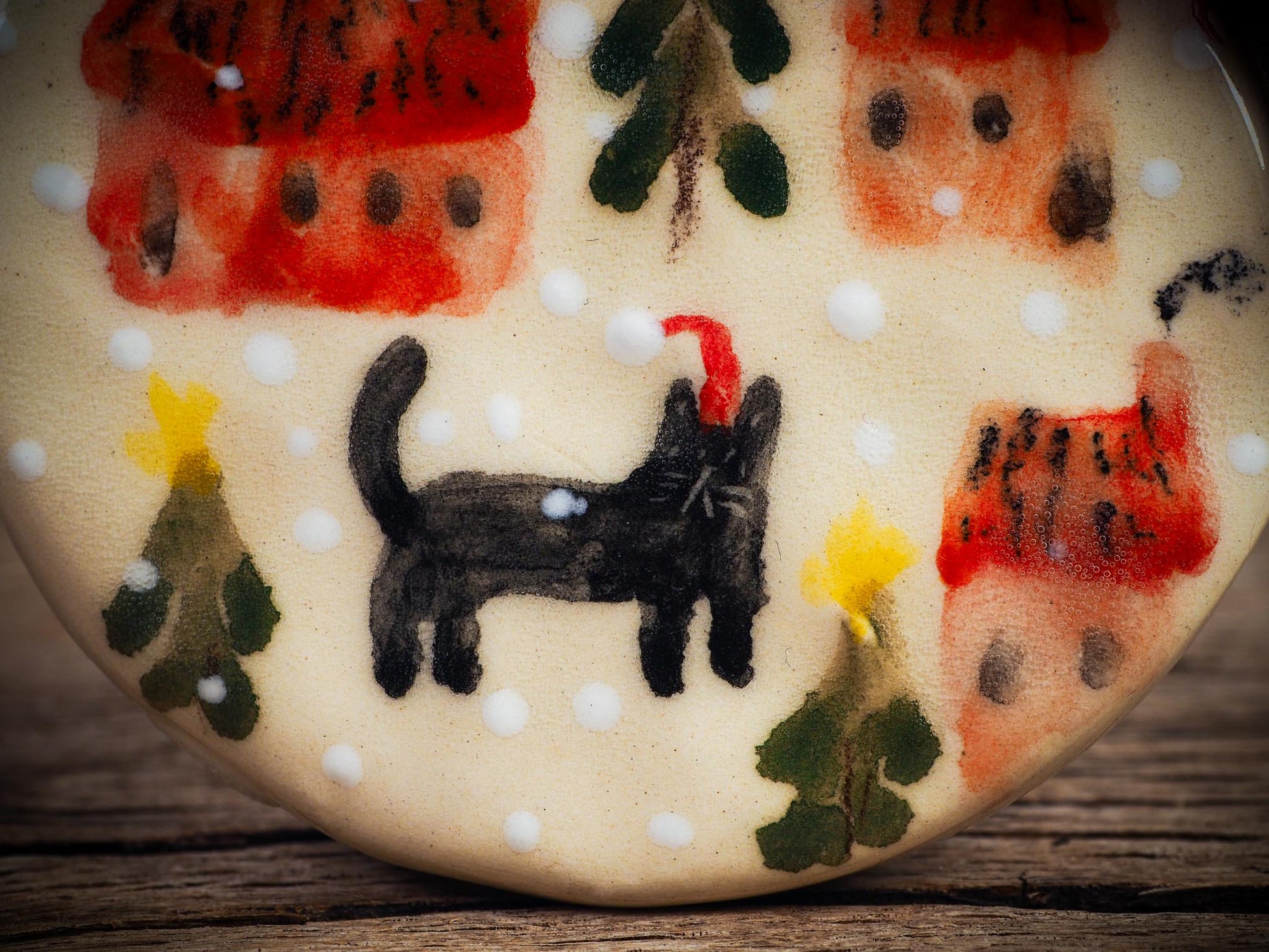 Handmade ceramic ornament of a black cat in a snowy village by Idania Salcido aka Danita Art.
