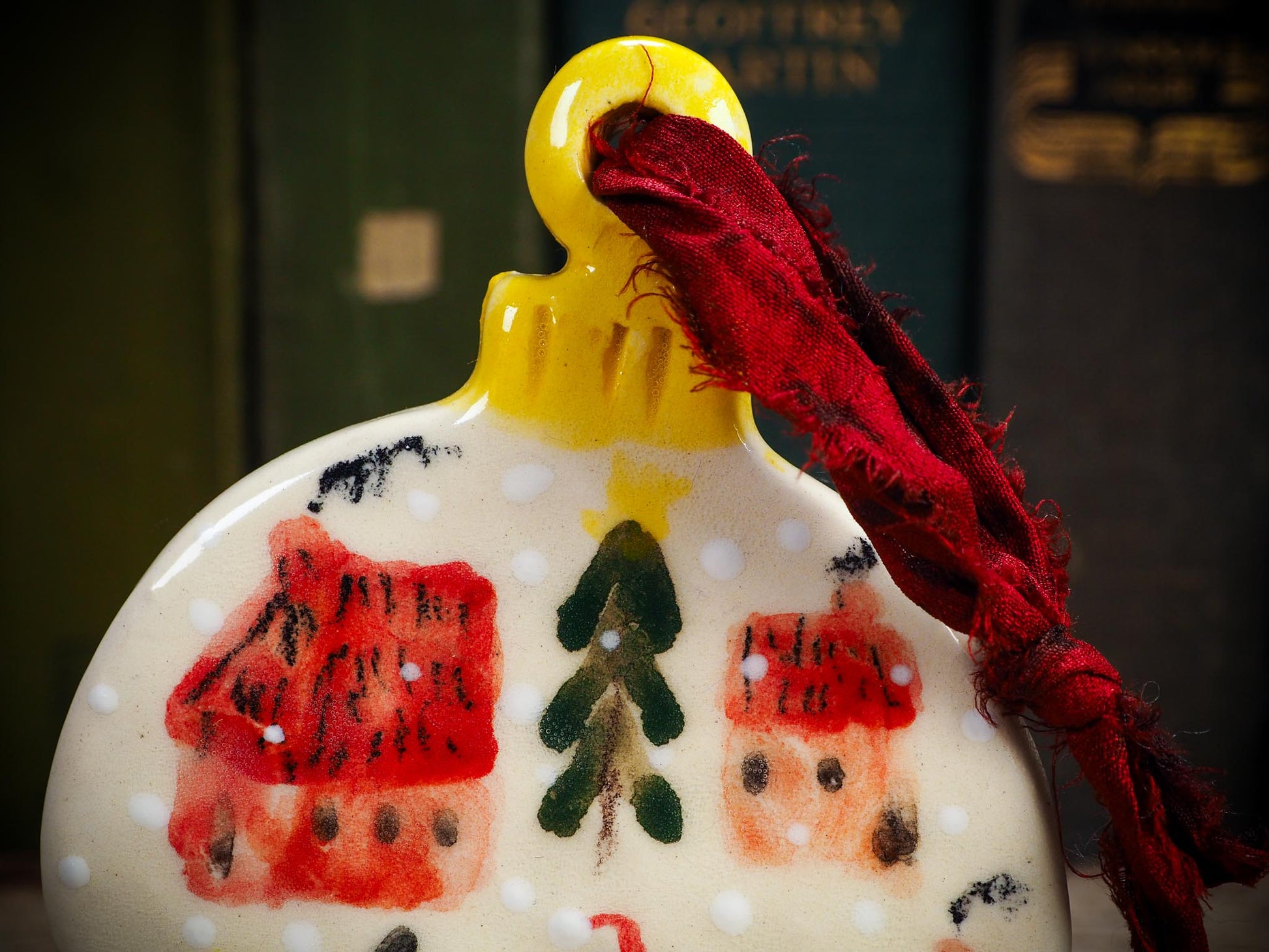 Handmade ceramic ornament of a black cat in a snowy village by Idania Salcido aka Danita Art.