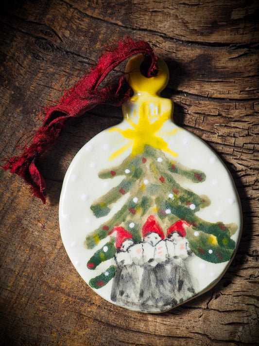 Handmade ceramic ornament of carolers under a Christmas tree by Idania Salcido aka Danita Art.