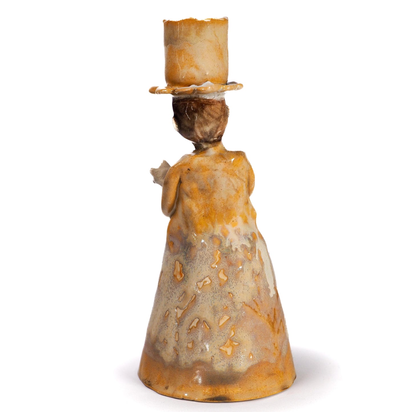 A vintage ceramic figurine of a woman from behind, wearing a tall top hat and a long dress with a mottled brown and beige glaze, set against a plain white background.