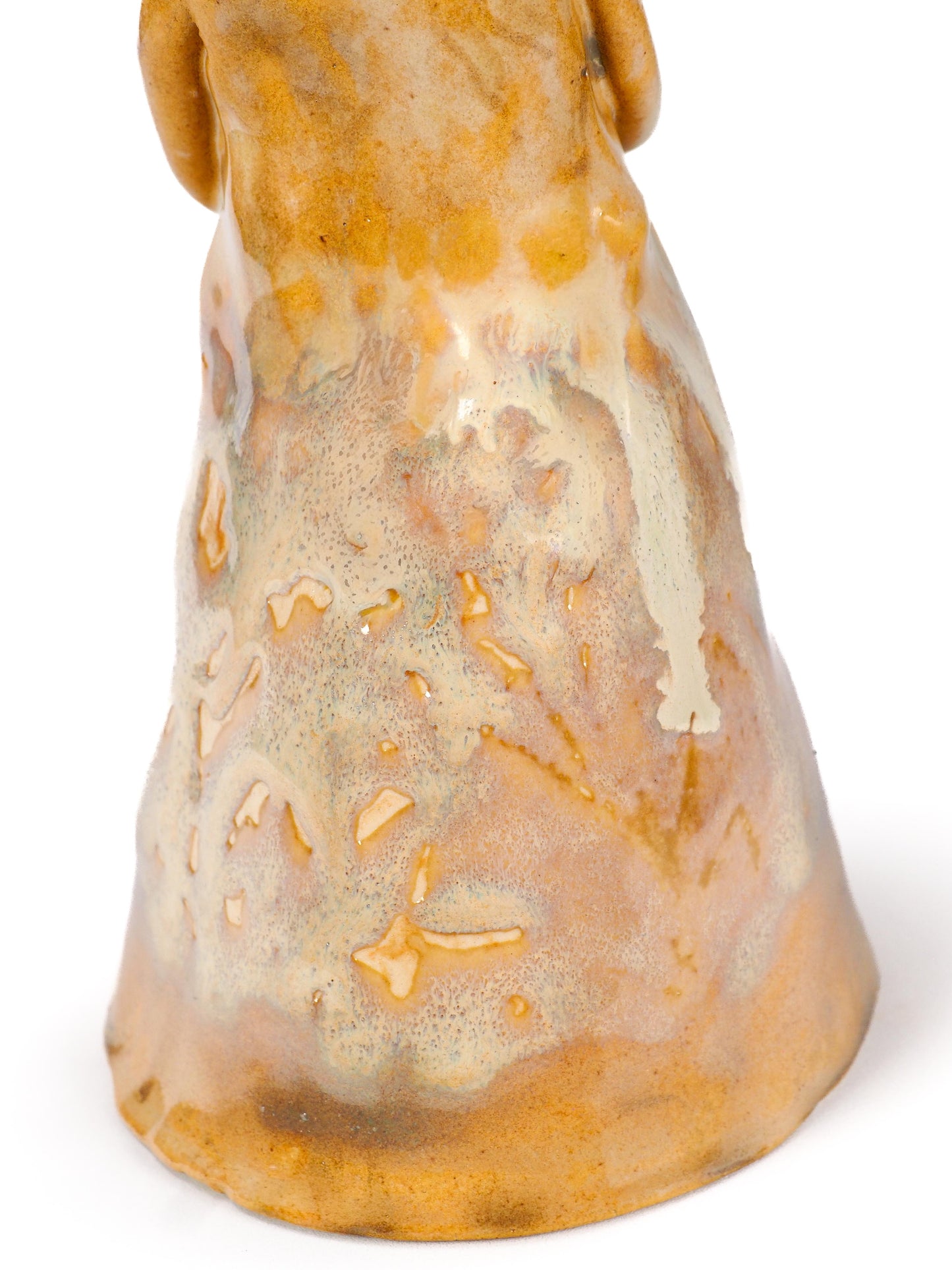 Close-up of a ceramic bell-shaped vessel or decorative object with a glossy glaze in warm tan, cream, and amber tones by Idania Salcido (Danita Art).