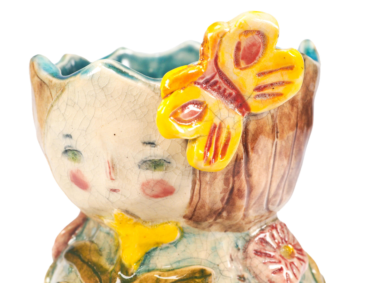 A close-up of a handcrafted ceramic planter shaped like a whimsical face with a large yellow butterfly on its head, featuring a rustic brown wood-grain texture and multicolored glaze details by Idania Salcido (Danita Art).