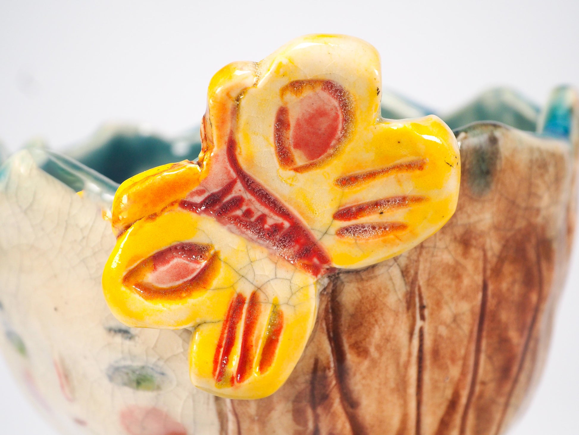 A close-up of a ceramic bowl featuring a prominent yellow butterfly decoration with red and orange accents on the front by Idania Salcido (Danita Art).
