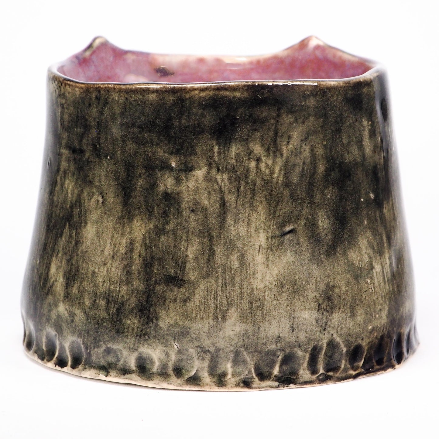 A handmade ceramic cup with a wide, flared shape, featuring a textured, mottled glaze in dark brown and black with a pinkish glaze visible on the inner rim by Idania Salcido (Danita Art).