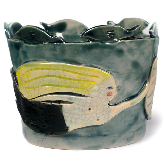 A handmade ceramic fish-shaped bowl with a dark green glazed finish, featuring a large yellow and white fish motif on the front and smaller fish protruding from the rim by Idania Salcido (Danita Art).