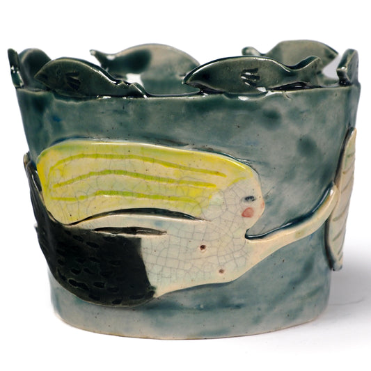 A handmade ceramic fish-shaped bowl with a dark green glazed finish, featuring a large yellow and white fish motif on the front and smaller fish protruding from the rim by Idania Salcido (Danita Art).
