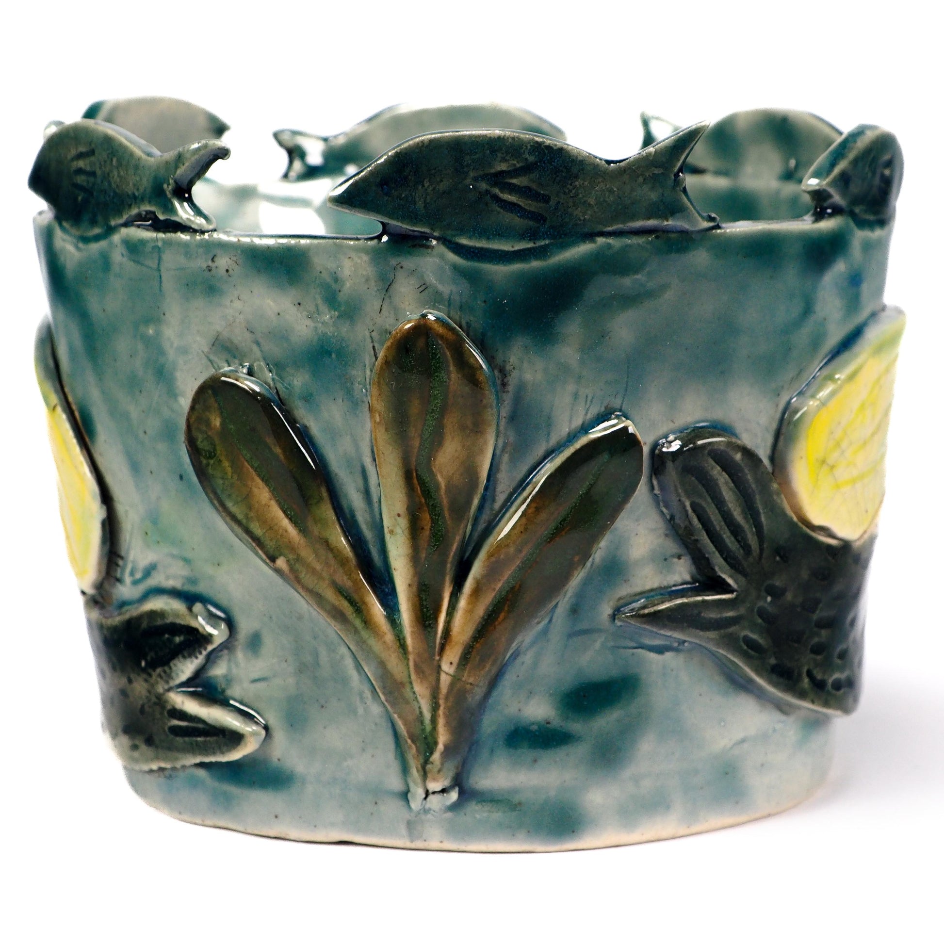 A handmade ceramic fish-themed planter or pot with a glazed finish in shades of teal, green, and brown, featuring raised fish and leaf motifs by Idania Salcido (Danita Art).