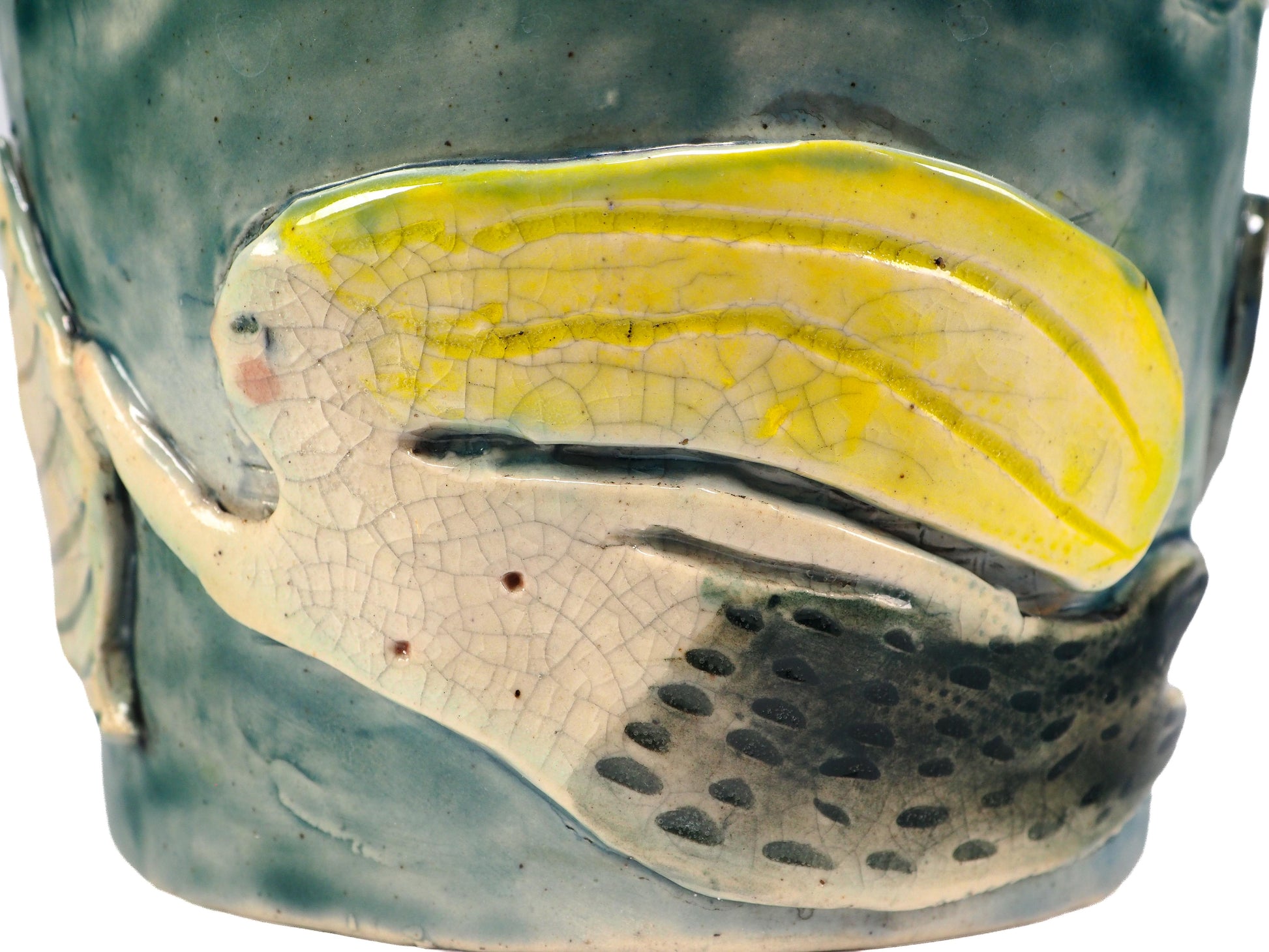Close-up of a ceramic fish-shaped decorative piece mounted on a textured blue-green cylindrical base, featuring a pale yellow and off-white fish with crackled glaze details by Idania Salcido (Danita Art).