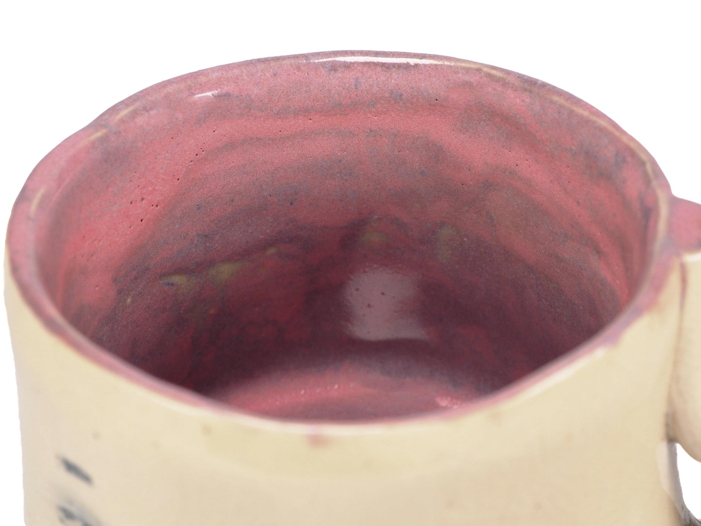 A handmade ceramic mug with a face design, featuring a beige stoneware body, hand-painted black eyes and eyebrows, pinkish-red cheeks, and a reddish-brown interior by Idania Salcido (Danita Art).