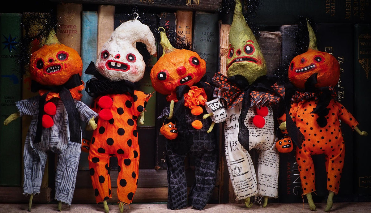 Five handmade Halloween dolls with creepy, stylized faces and mismatched outfits posed in front of a row of vintage books.
original handmade spun cotton Halloween art dolls by Idania Salcido (Danita Art).