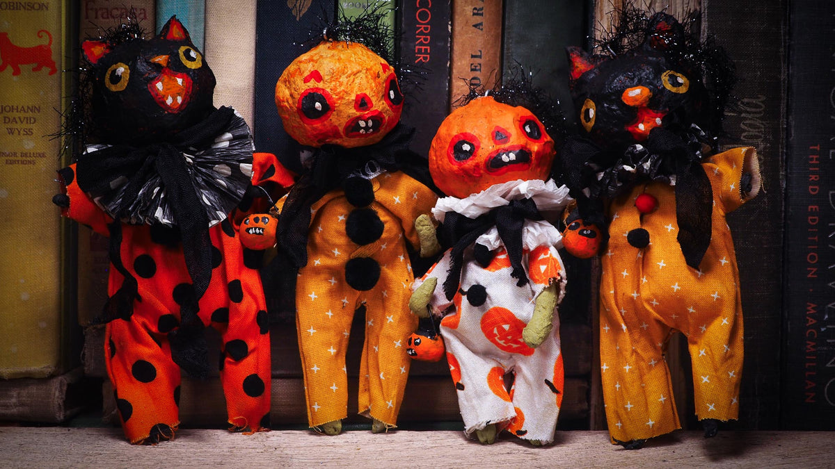 Four handmade Halloween dolls dressed as cats and pumpkins, posed in front of a row of vintage books.
Original spun cotton hand made Halloween doll ornament by Idania Salcido (Danita Art)