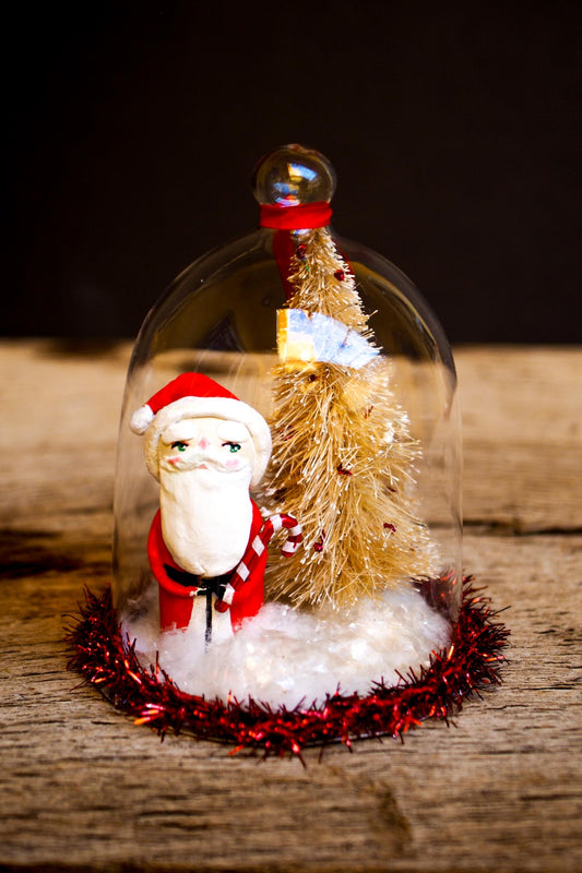 An original handmade christmas tree ornament by Idania Salcido. A clear domed diorama with a holiday scene with Santa Claus elves, Christmas Trees, Elves, Gifts and magical glitter deer. Perfect to decorate your Christmas Tree, your mantelpiece or to be used as accents on a dinner table.