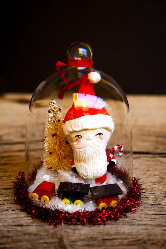 An original handmade christmas tree ornament by Idania Salcido. A clear domed diorama with a holiday scene with Santa Claus elves, Christmas Trees, Elves, Gifts and magical glitter deer. Perfect to decorate your Christmas Tree, your mantelpiece or to be used as accents on a dinner table.