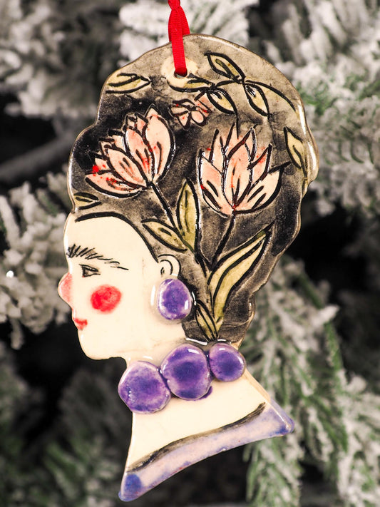 An original Christmas Holiday tree round glazed ceramic hanging ornament handmade by Idania Salcido, the artist behind Danita Art. Glazed carved sgraffito stoneware, hand painted and decorated, it is illustrated by hand with flowers, hearts, leaves, nature patterns and the face of Frida Kahlo.