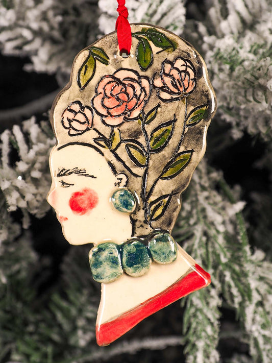 An original Christmas Holiday tree round glazed ceramic hanging ornament handmade by Idania Salcido, the artist behind Danita Art. Glazed carved sgraffito stoneware, hand painted and decorated, it is illustrated by hand with flowers, hearts, leaves, nature patterns and the face of Frida Kahlo.